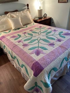 a bed with a purple and green quilt on it