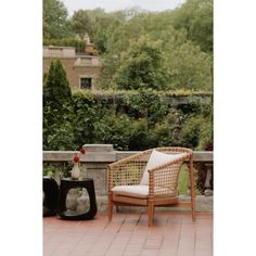 a wicker chair sitting on top of a brick patio next to a vase with flowers