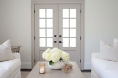 a living room with two white couches and a coffee table in front of the door