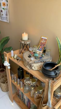 a wooden shelf filled with lots of items next to a candle and potted plant