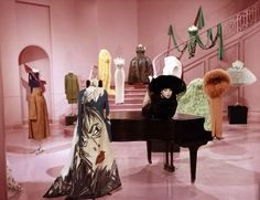 a room filled with mannequins and dresses on display in front of a piano