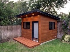 a small wooden shed sitting on top of a lush green field