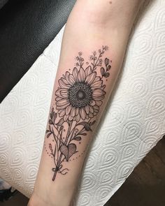 a black and white sunflower tattoo on the arm