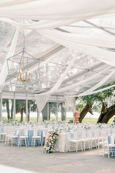 the inside of a tent with tables and chairs set up for an outdoor wedding reception