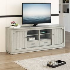 a flat screen tv sitting on top of a wooden entertainment center in a living room