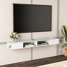 a flat screen tv mounted to the side of a wall next to a potted plant