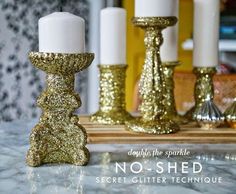 gold glitter candlesticks are sitting on a table next to each other with white candles