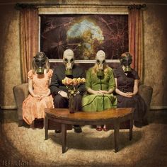 three people wearing masks sitting on a couch in front of a table with vases