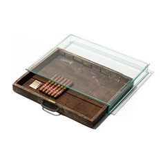 an old wooden box filled with cigars on top of a white surface and glass lid