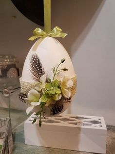 an egg decorated with flowers and feathers on a table