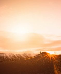 a person standing on top of a snow covered mountain under a bright sky with the sun behind them