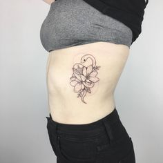 a woman's stomach with a flower tattoo on her side, and the bottom part of her belly