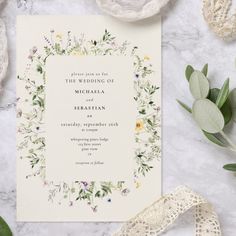 the wedding card is surrounded by greenery and lace