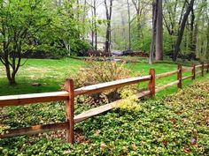 a wooden fence surrounded by green grass and trees