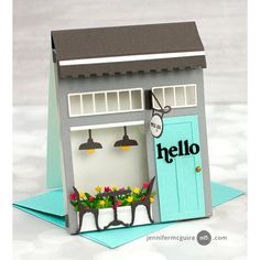 a paper house with flowers in the window and an open door that says hello on it