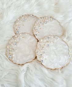 three white plates with pearls on them sitting on a fur covered tablecloth, one is gold and the other is silver