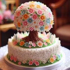 two tiered cake decorated with flowers and a tree