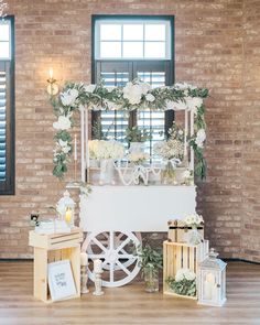 a white table with flowers and candles on it in front of a brick wall at a wedding