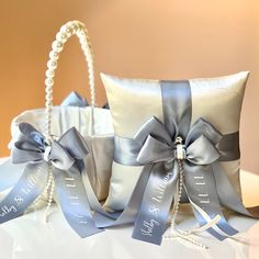 a ring pillow with pearls and ribbon tied around it, sitting on a white table