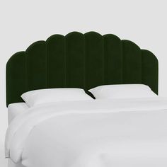 a green headboard with white sheets and pillows