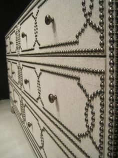 the drawers are decorated with beading and metal knobs on each drawer, which is lined with pearls