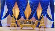 a couch and two chairs in front of blue drapes with gold trimmings