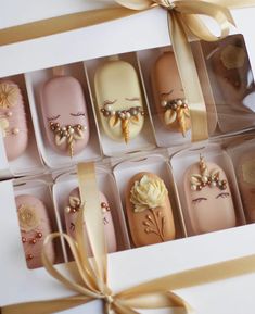 a box filled with lots of different colored nail polishes next to a gold ribbon