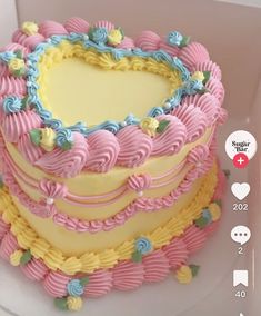 a heart shaped cake sitting on top of a white plate with blue and yellow frosting