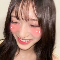 a young woman with pink eyes and long dark hair smiles at the camera while wearing white polka dots on her face