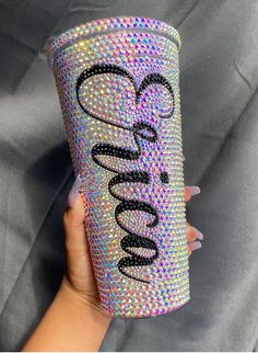 a hand holding a cup with the word love on it and some glitter in front of it