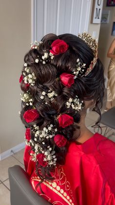 a woman sitting in a chair with flowers in her hair and wearing a tiara