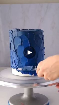 someone is decorating a cake with blue icing on a silver platter,