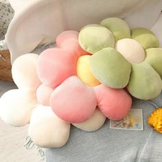 a pile of pillows sitting on top of a bed next to an orange and yellow flower