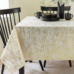 the table is set with two black chairs and a white lace tablecloth on it