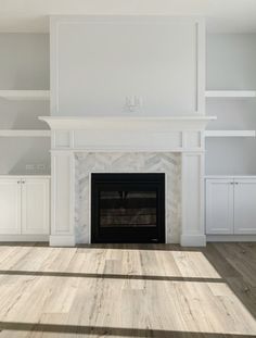 an empty living room with a fireplace and white cabinets on either side of the fire place