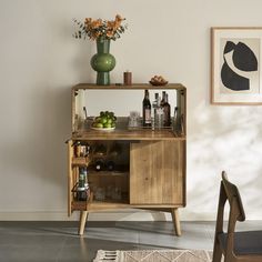 a wooden cabinet with bottles and glasses on it next to a chair in a room