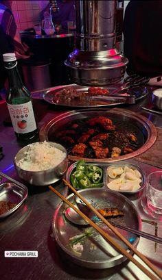 a table topped with lots of food and chopsticks next to bowls filled with vegetables