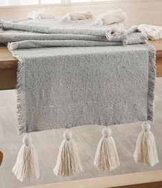 three tasselled towels sitting on top of a wooden table