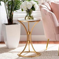 a pink chair next to a table with white flowers on it and a potted plant