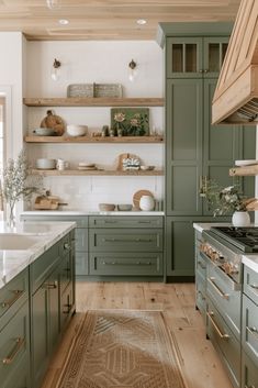 a kitchen with green cabinets and white counter tops, an area rug on the floor