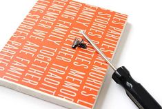 a pair of scissors sitting on top of an orange and white book with words written across it