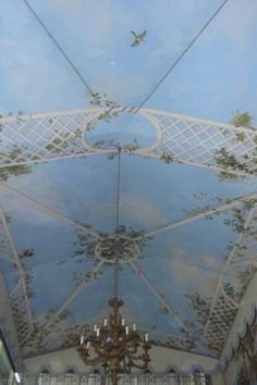 an ornate ceiling with chandelier and blue sky in the background