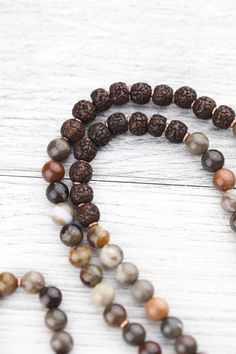 Limited to 10. Our new 9 Eye Dzi Mala combines Petrified Wood beads, powerful Rudrakshas, vintage brass spacers, and a Bodhi Seed guru bead. DharmaShop founder, Sander Cohen, sourced this 9 Eye Dzi bead on his last trip to Taiwan in 2019. Although it isn't ancient, this is one of the more exceptional beads made in the early 1990's. Because it is from the earth and was once organic material, Petrified Wood is known for its strong grounding properties and calming energies. This exclusive DharmaSho Spiritual Beaded Necklace With Spacer Beads For Festivals, Spiritual Beaded Necklaces With Spacer Beads For Festivals, Brown Mala With Natural Stones, Brown Mala With Natural Stones And Round Beads, Brown Mala With Natural Round Beads, Bohemian Brown Mala For Rituals, Spiritual Brown Gemstone Beads, Bohemian Brown Mala With Natural Stones, Spiritual Beaded Necklaces With Natural Stones For Festivals