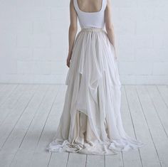 a woman in a white dress standing on a wooden floor with her back to the camera