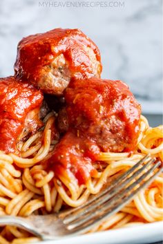 spaghetti and meatballs are piled on top of each other with a fork in the foreground