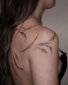 the back of a woman's shoulder with feathers drawn on her left arm and chest