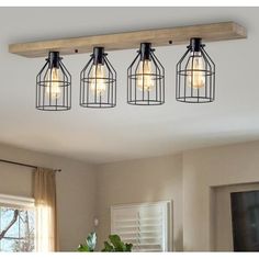 four lights hanging from a wooden beam in a living room