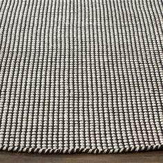 a white and grey rug on top of a wooden table with a black chair in the background