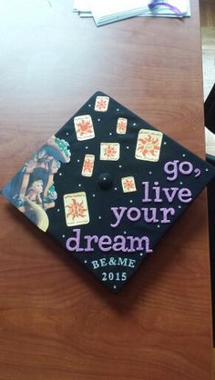 a graduation cap with the words go live your dream written on it sitting on top of a desk