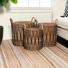 three woven baskets sitting on top of a rug next to a plant in a living room